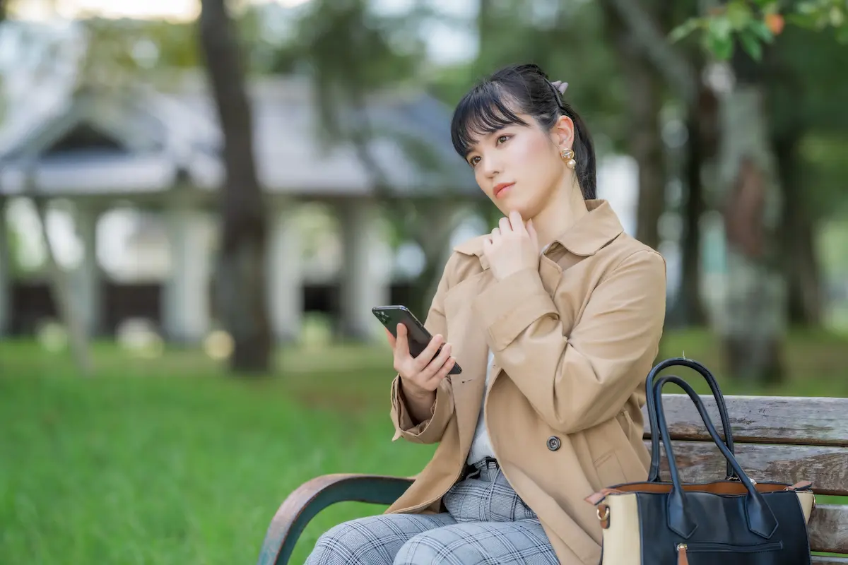 スマホを手に考え込む女性